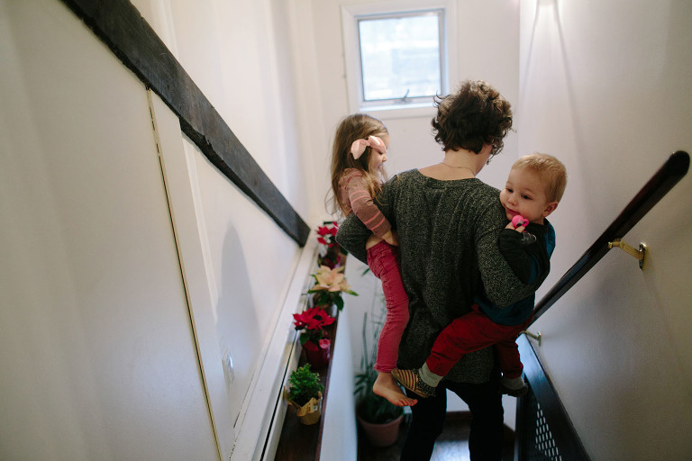 mom carrying two kids downstairs