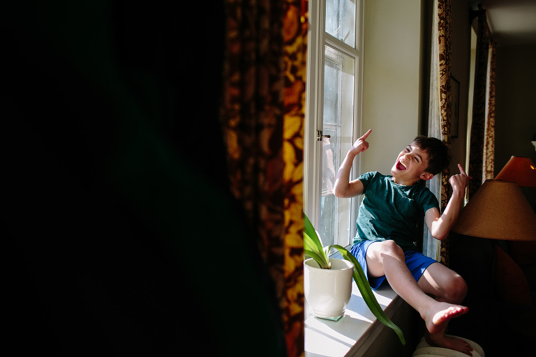 boy on windowsill in home documentary