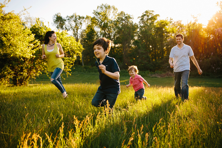 family running through field at sunset