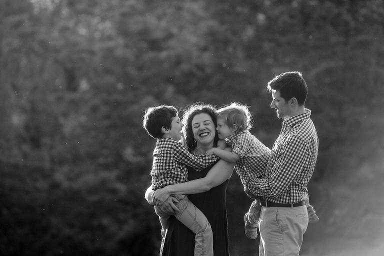 boys kissing their mom outside at sunset