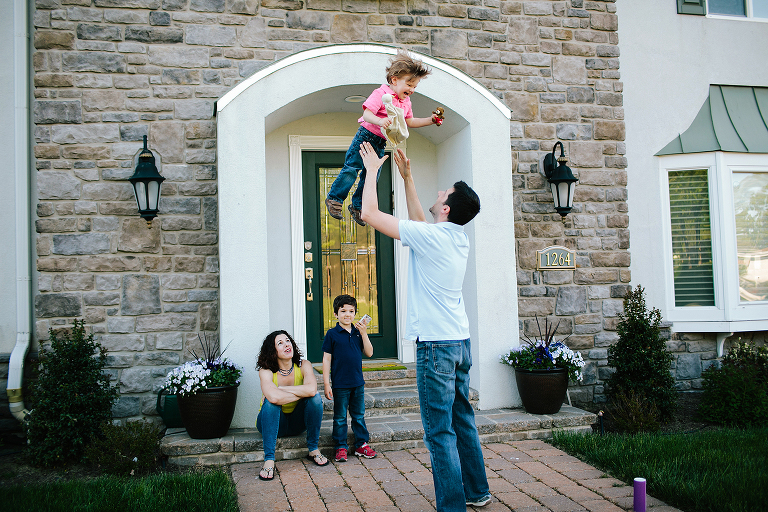 toddler being thrown in the air in front of a house