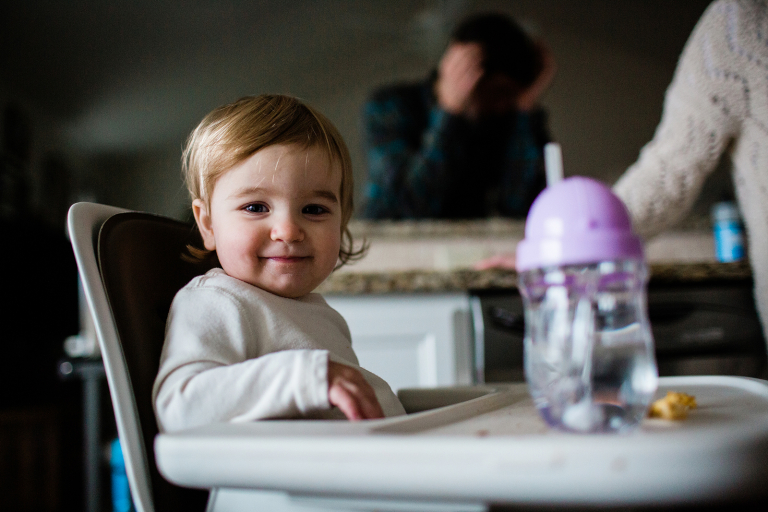 toddler sitting in a highchair smiling at the camera