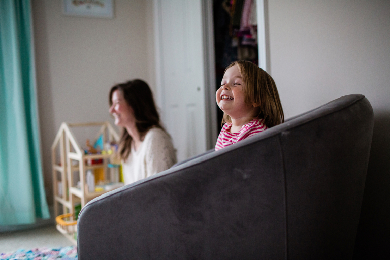 documentary photo of girl smiling with her mom in the background smiling