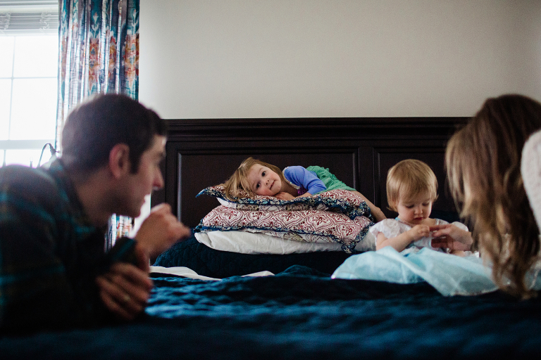 family on bed with two girls dressed in princess dresses