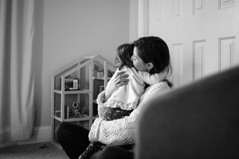 in home family session candid black and white photograph of mom hugging toddler daughter