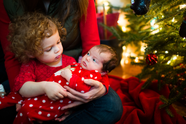 Image of big sister holding newborn and gazing into her face