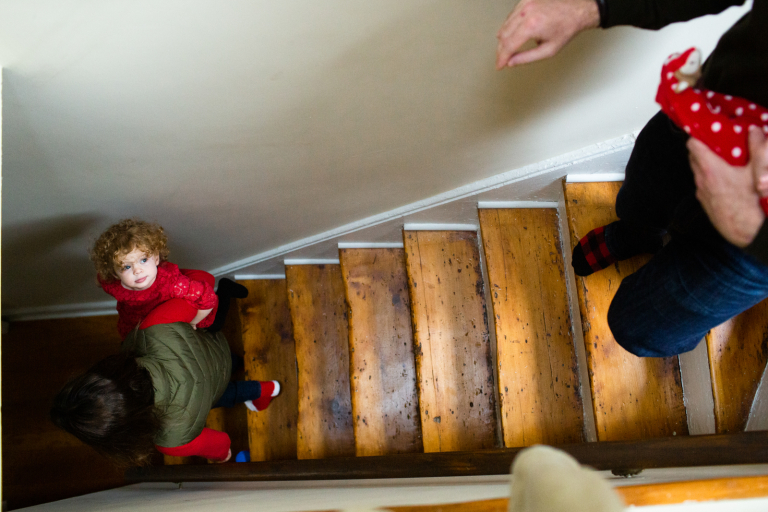 Image from above of family walking down steps with toddler girl looking back up at her dad