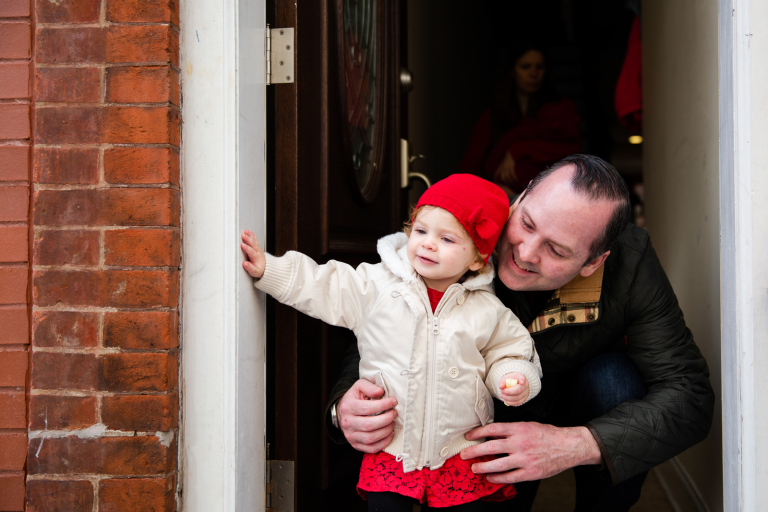 Photograph of toddler girl and her dad cuddling in the doorway of their Philadelphia home before heading outside