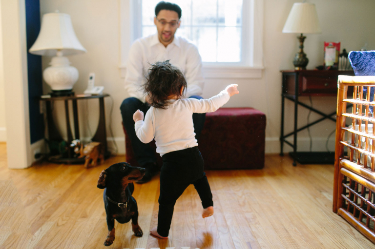 Image of little girl walking towards her dad with dog next to her