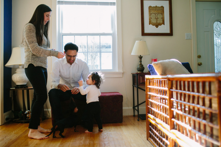 image of family sitting in front of a window feeding their dog