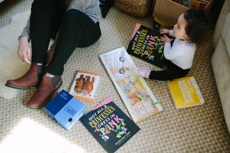 Detail image of mom and toddler girl sitting with books on the floor
