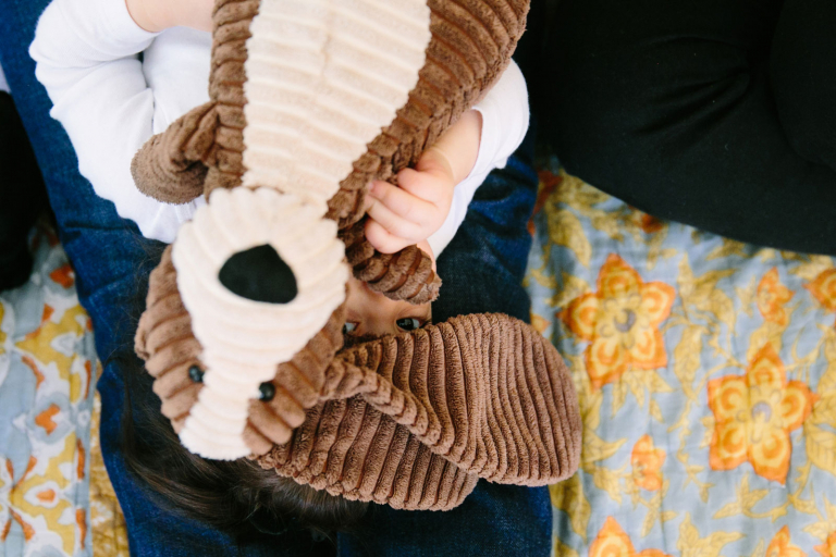 Documentary image of little girl playing peek-a-boo with stuffed dog