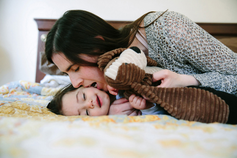 documentary image of mom biting toddler girl's cheek playfully