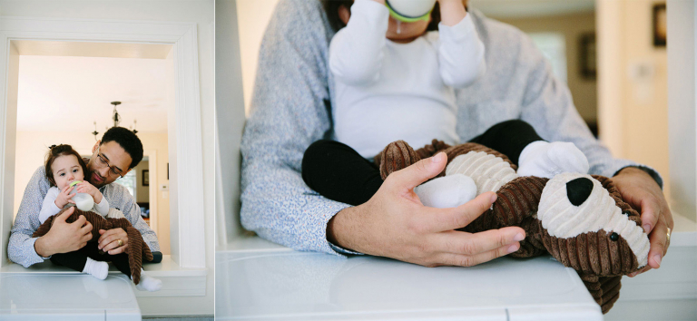 documentary image of little girl sitting in kitchen pass through with dad and stuff dog drinking a bottle