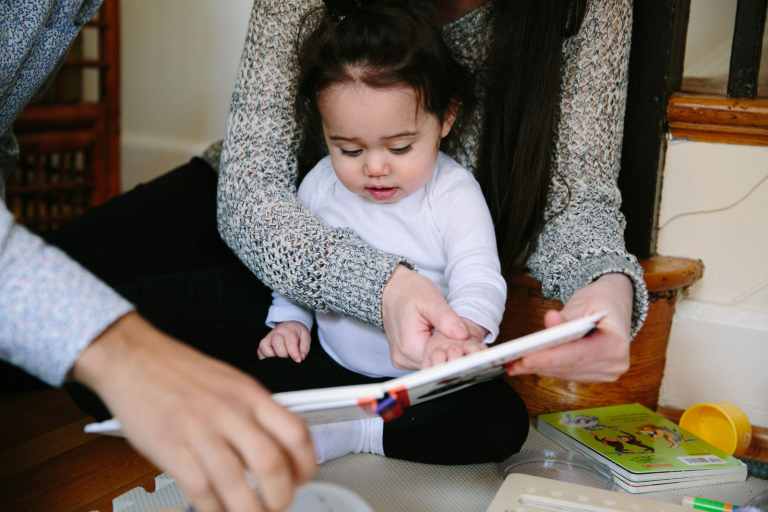Closeup image of little girl reading with her parents