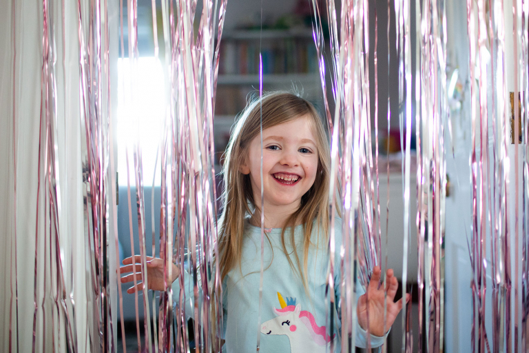 Little girl looking at the camera through sparkly streamers