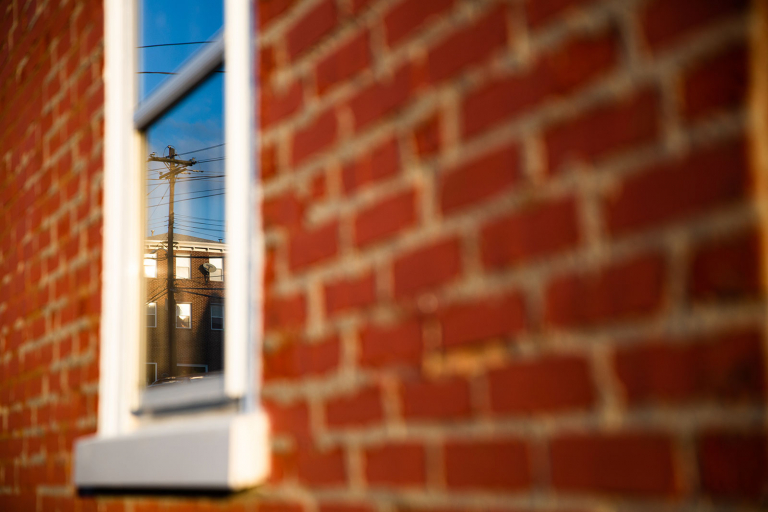 Street photograph of brick wall with reflection in a window.