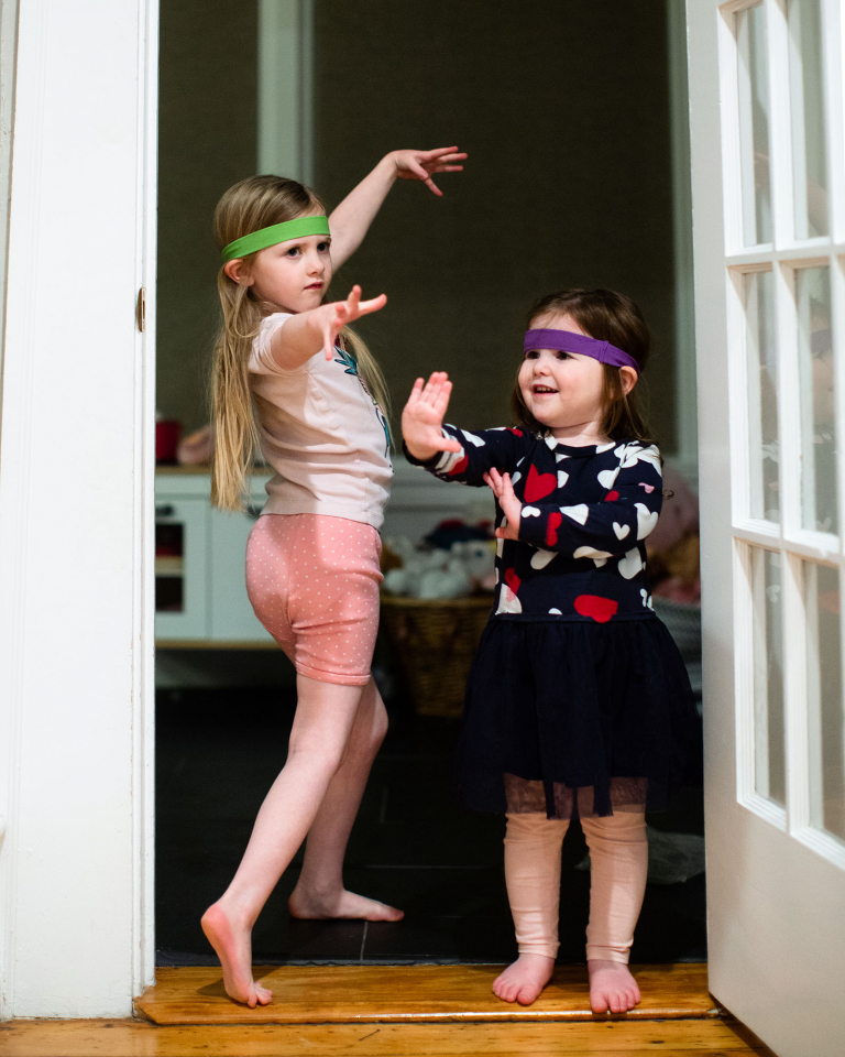 Two girls in martial arts poses with headbands on their foreheads.