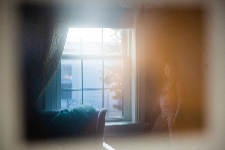 Reflection image of girl standing near a window