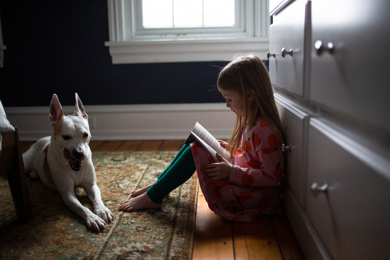 Image of little girl reading with her dog