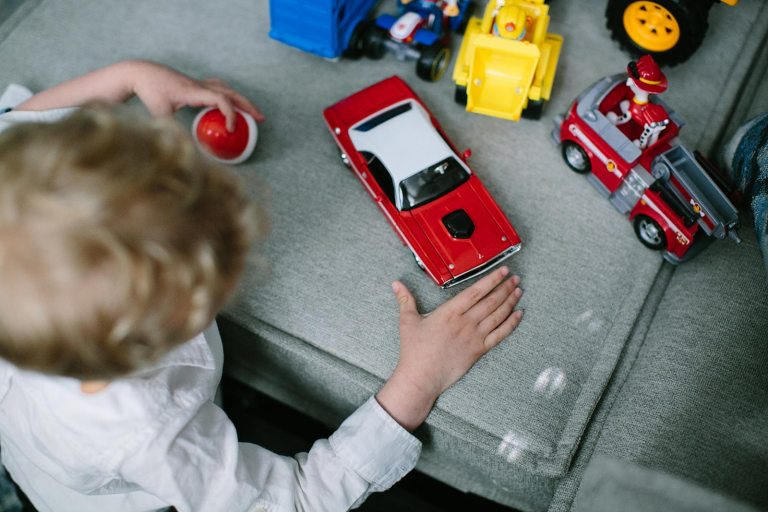 Overhead photograph of little boy playing with cars.