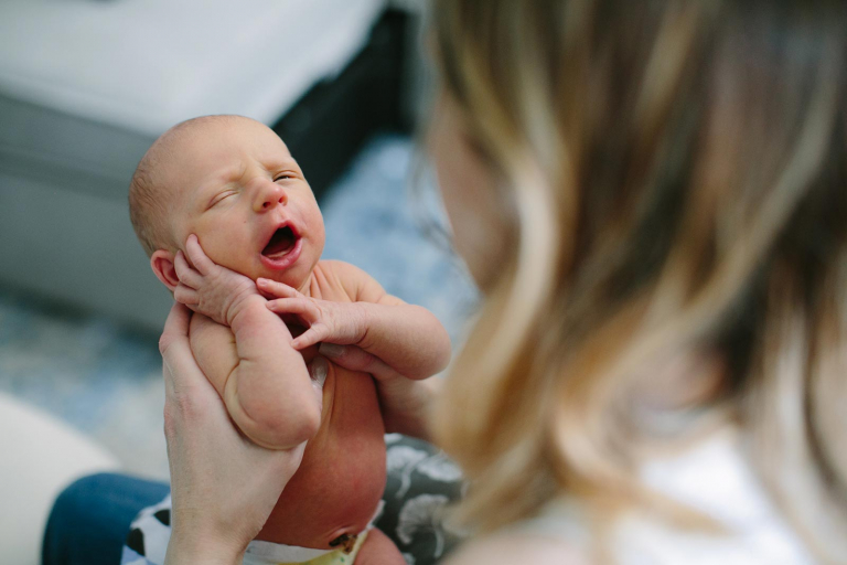 Documentary photo of newborn baby in mom's hands yawning