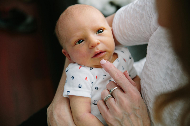 Closeup image of newborn looking up at grandmother.