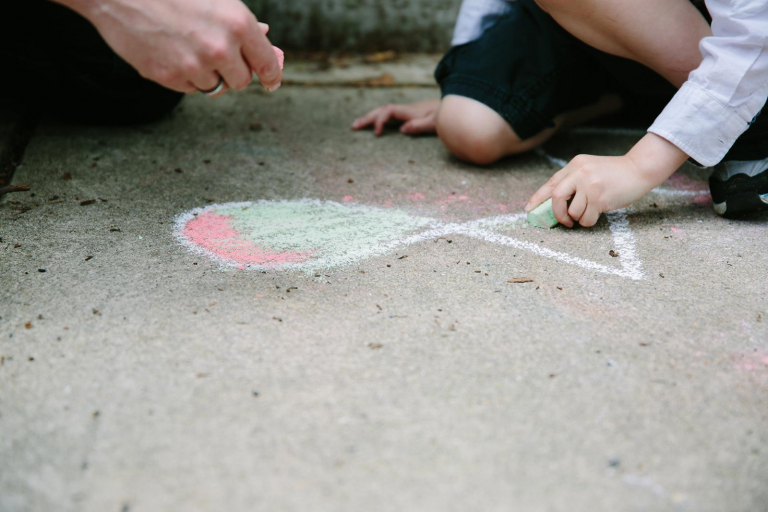 documentary photograph of dad and little boy drawing with chalk