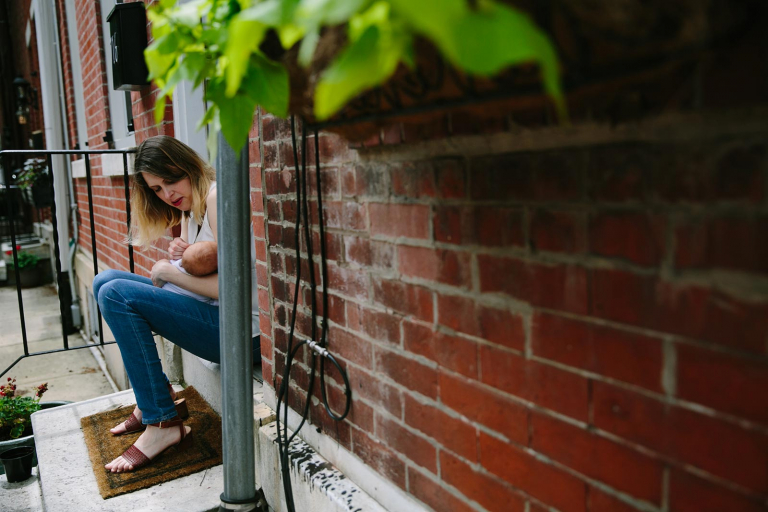 Philadelphia documentary newborn photographer image of mom cuddling newborn on front step
