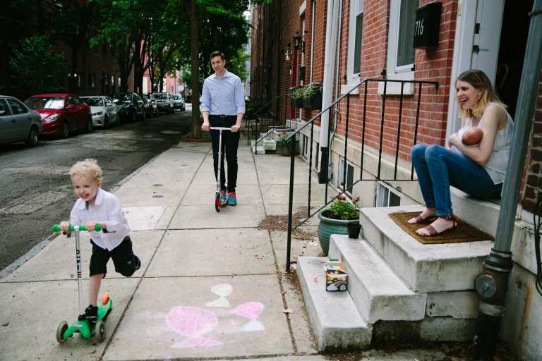 Philadelphia documentary photograph of family riding scooters in front of home