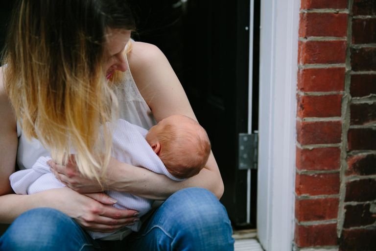 Newborn photograph of mom and baby on front step
