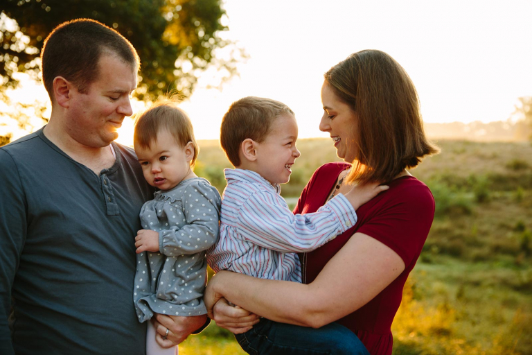 Photograph of family snuggling with kids at sunrise in valley forge park