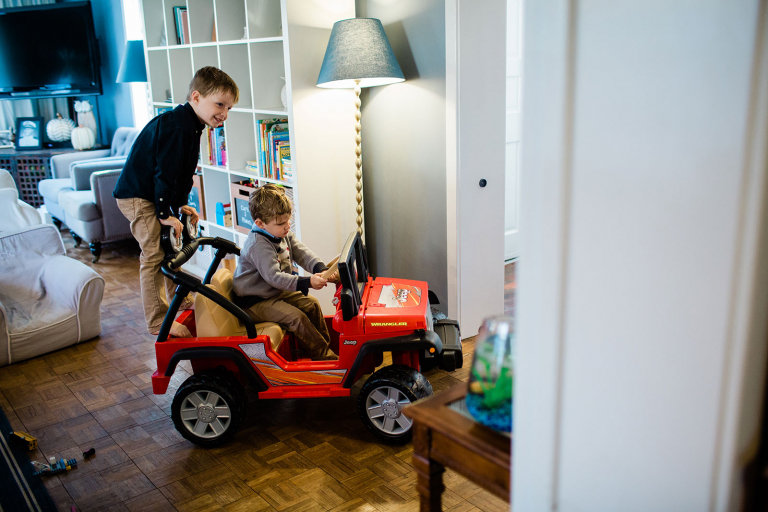 family photograph of two boys riding a car through house
