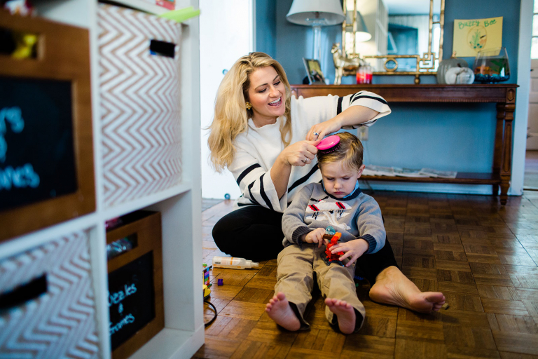 Photograph of mom brushing little boy's hair on the floor