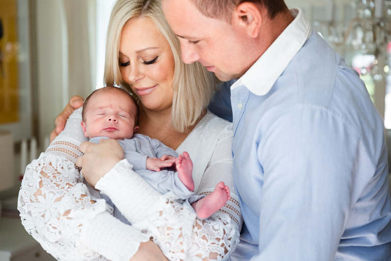 parents snuggling with newborn baby in classic at home newborn session