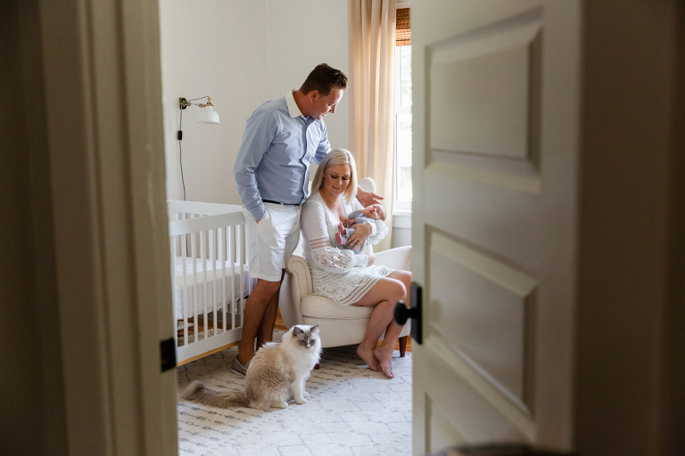 Gazing through doorway at new family of three and cat in classic at home newborn session