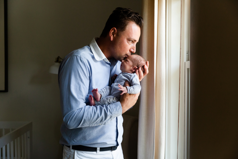 Dad kissing baby on the head in classic at home newborn photography session