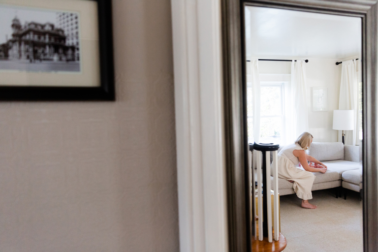 mom changing newborn baby's clothes in mirror